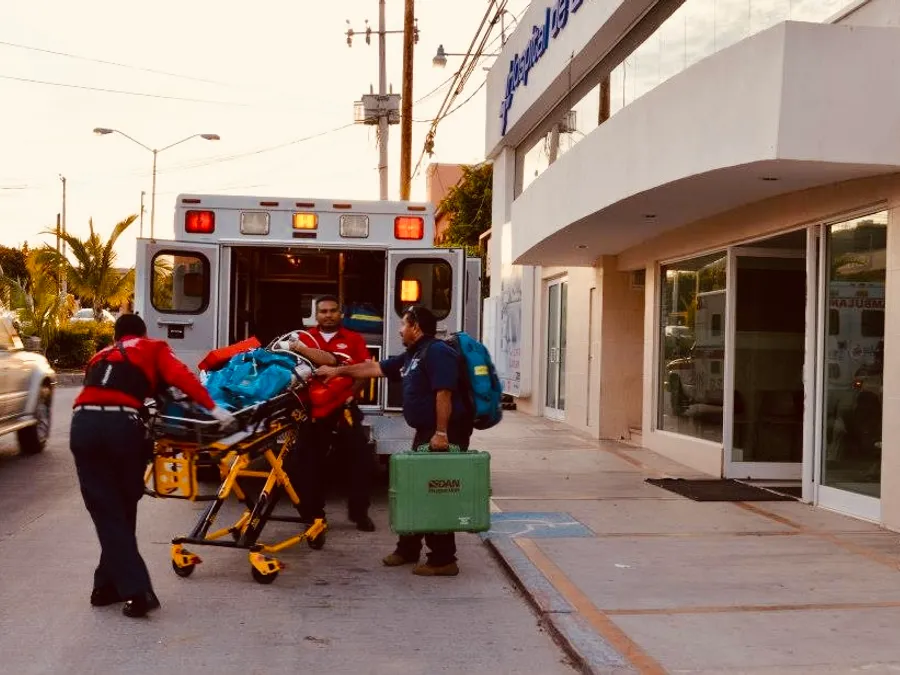 Paramédicos subiendo a un paciente en camilla a una ambulancia en una calle de Cabo San Lucas