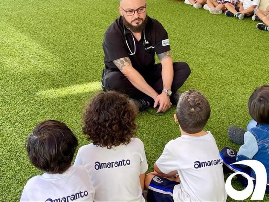 Instructor enseñando primeros auxilios a un grupo de niños pequeños sentados en el pasto
